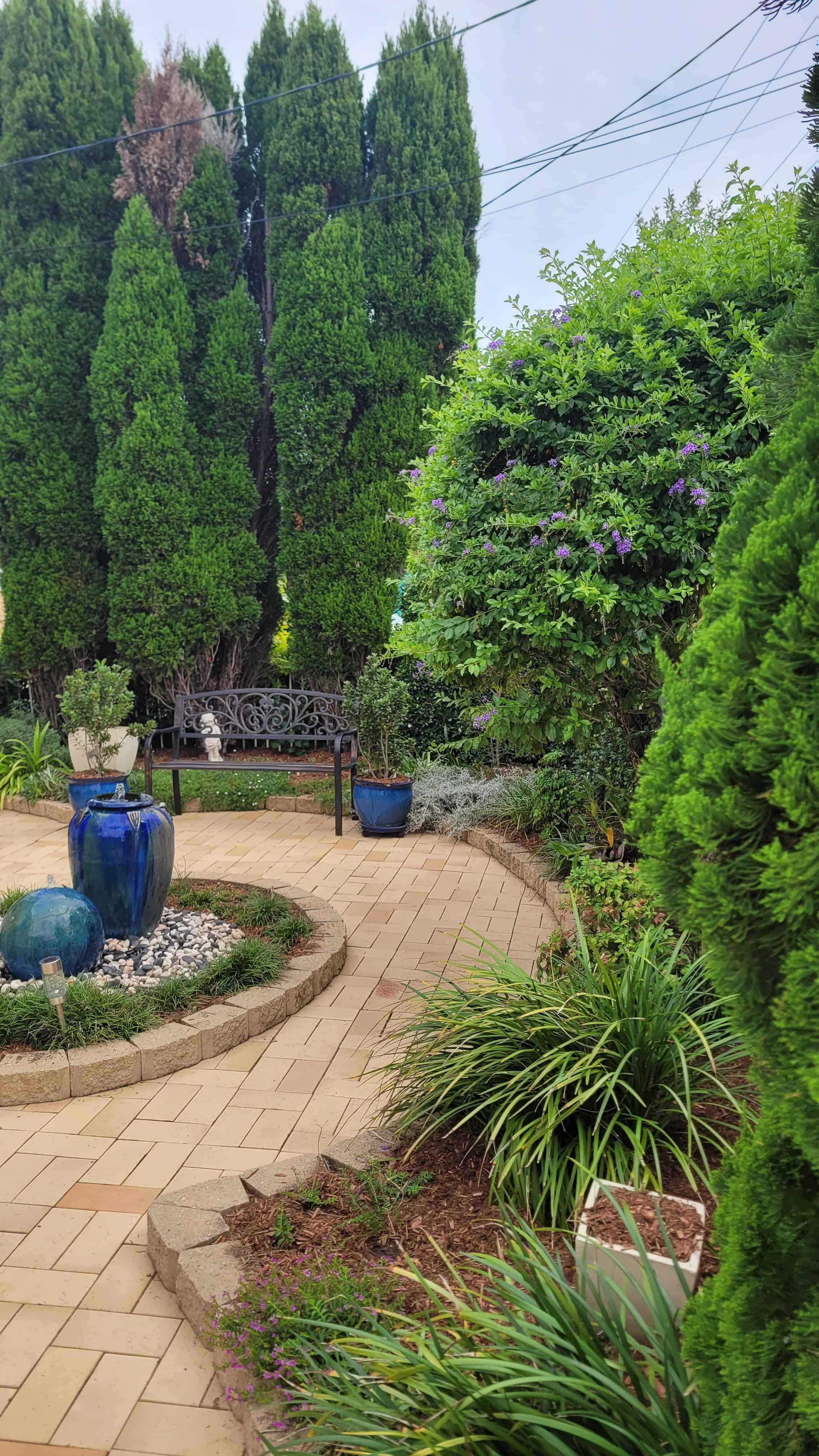 Paved garden area with water feature in the middle.