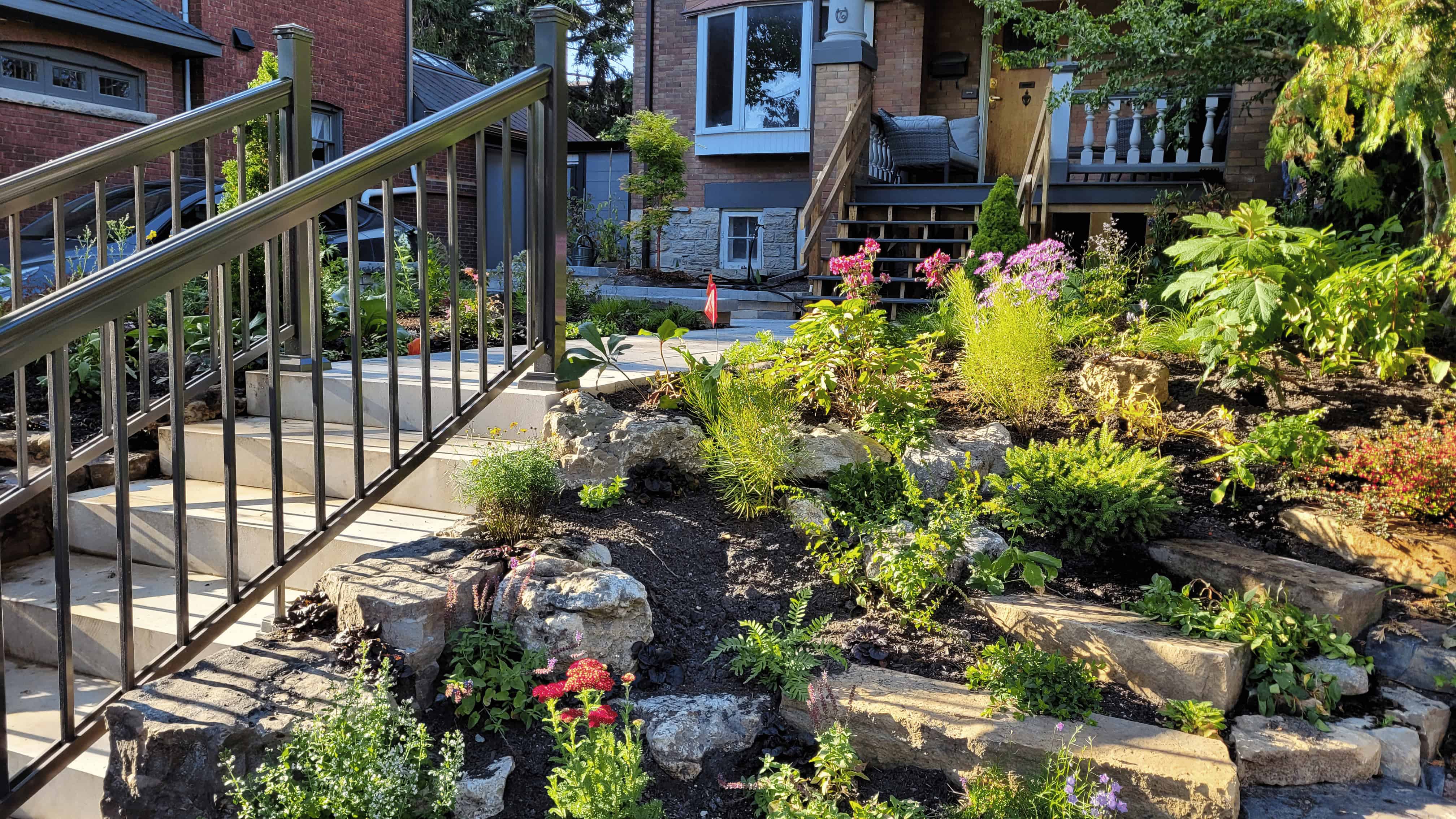 A serene garden with a stone path and stairs guiding towards a charming house nestled amidst nature's beauty.